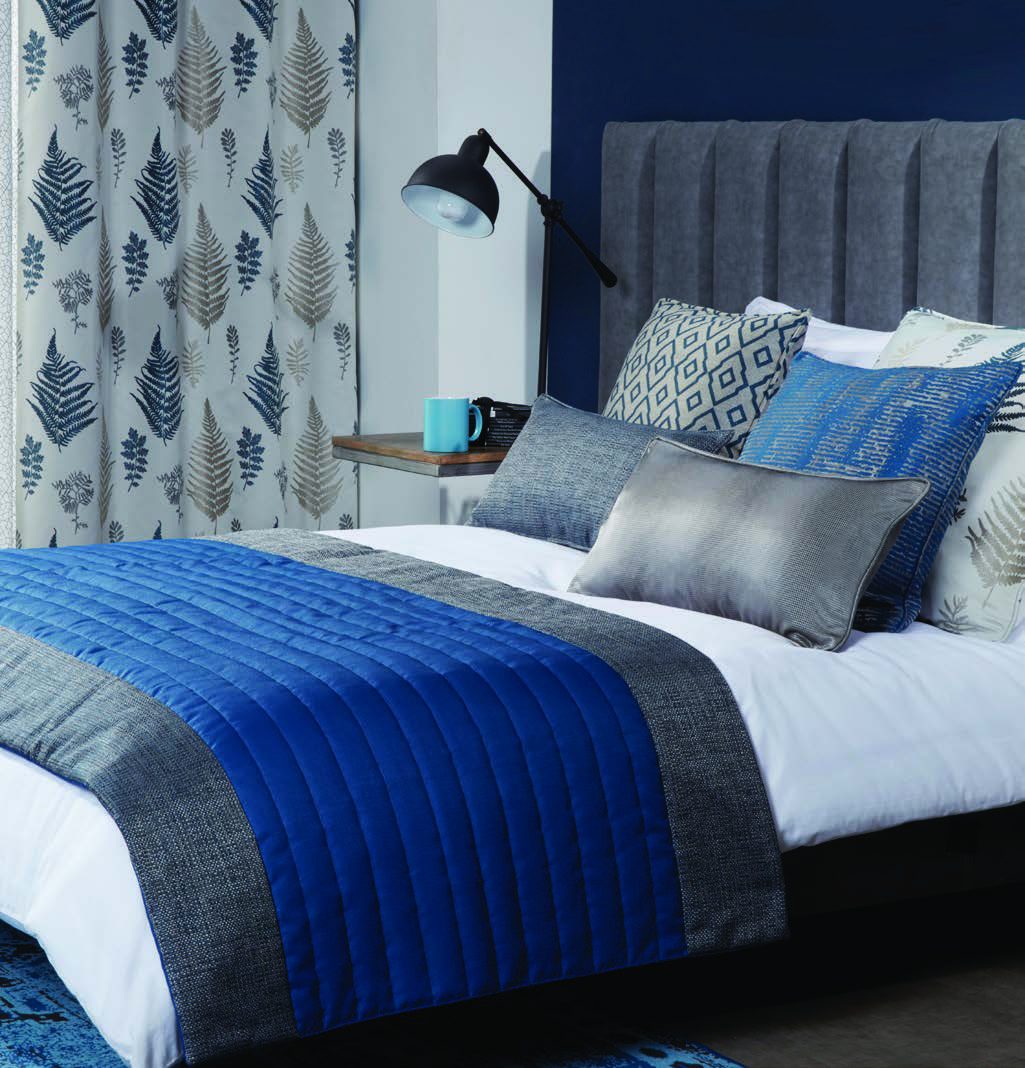 Guest-room bedding, pillows, and drapery in layered blues and greys