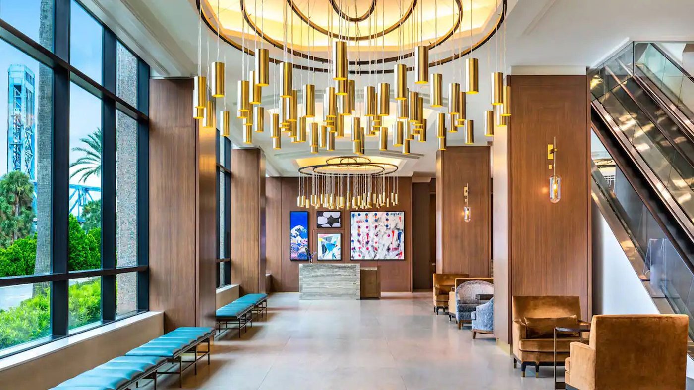 Bright hotel lobby with gold pendants and daylight — hospitality interiors represented by Erin Kennedy