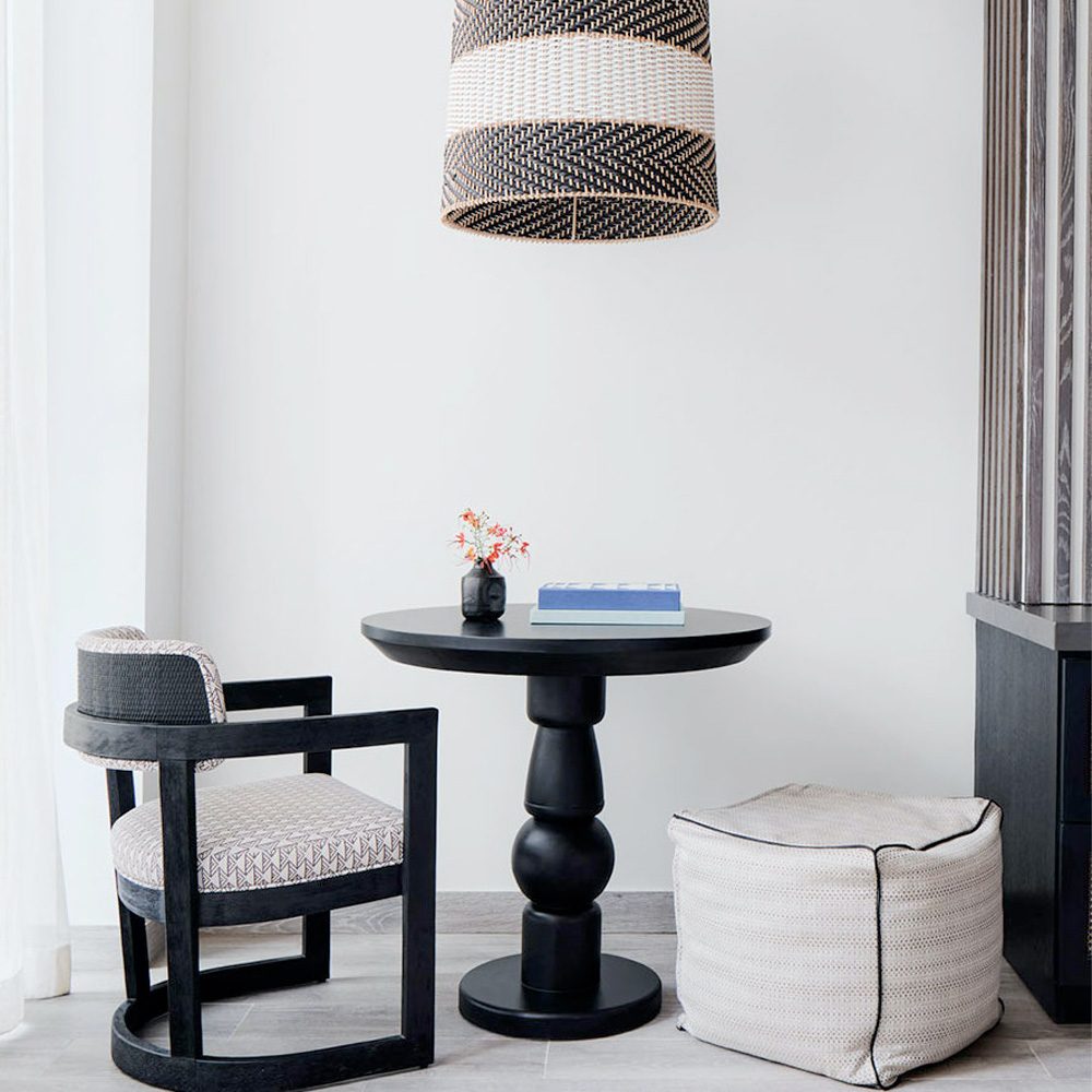 Lounge corner with a woven pendant, armchair, and pedestal table