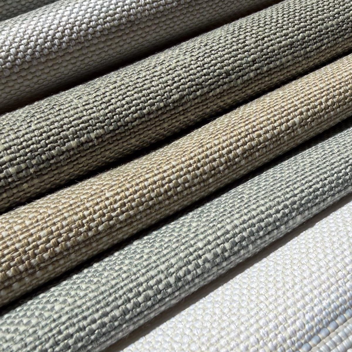 Stacked rolls of woven hospitality textiles in natural tones