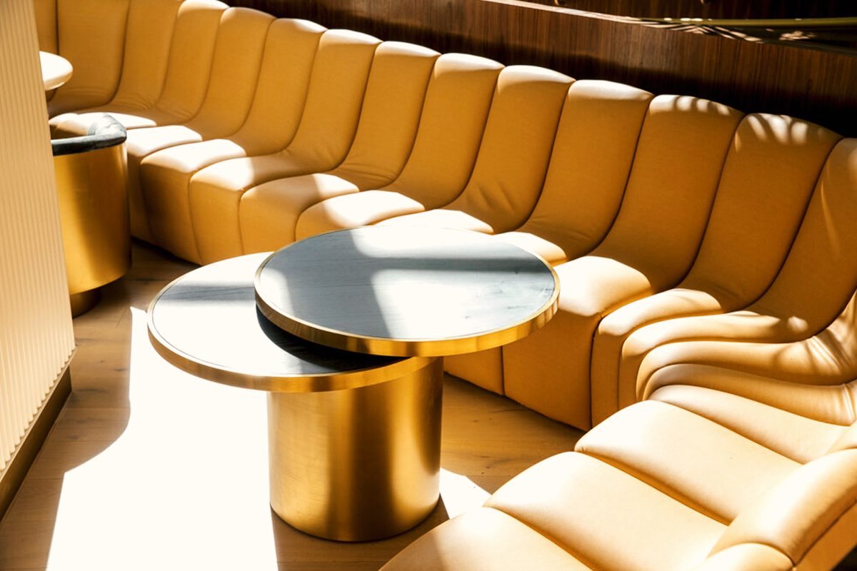 Curved lounge sofa and brass tables in daylight